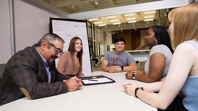 Indoor photo of instructor and students around a table